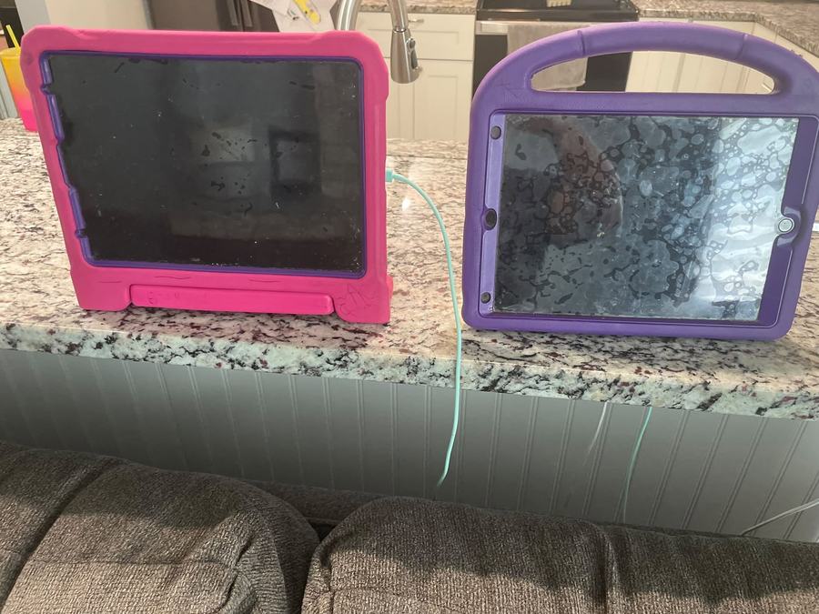 Two children's iPads left plugged in on the kitchen counter.