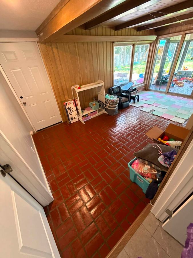 A tidy playroom with a swept brick-red floor.