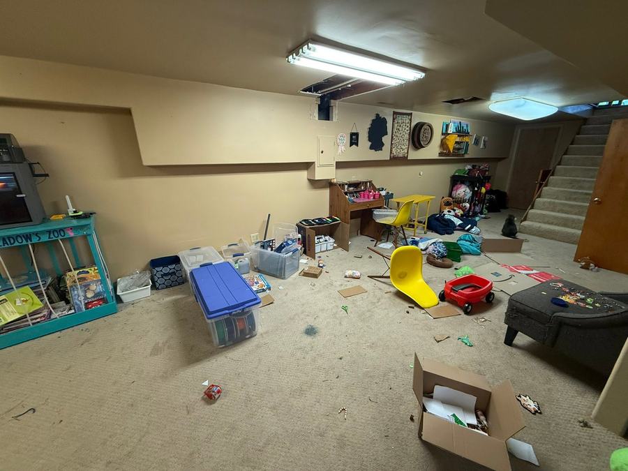 The wider basement before, with boxes and toys spread across the floor.